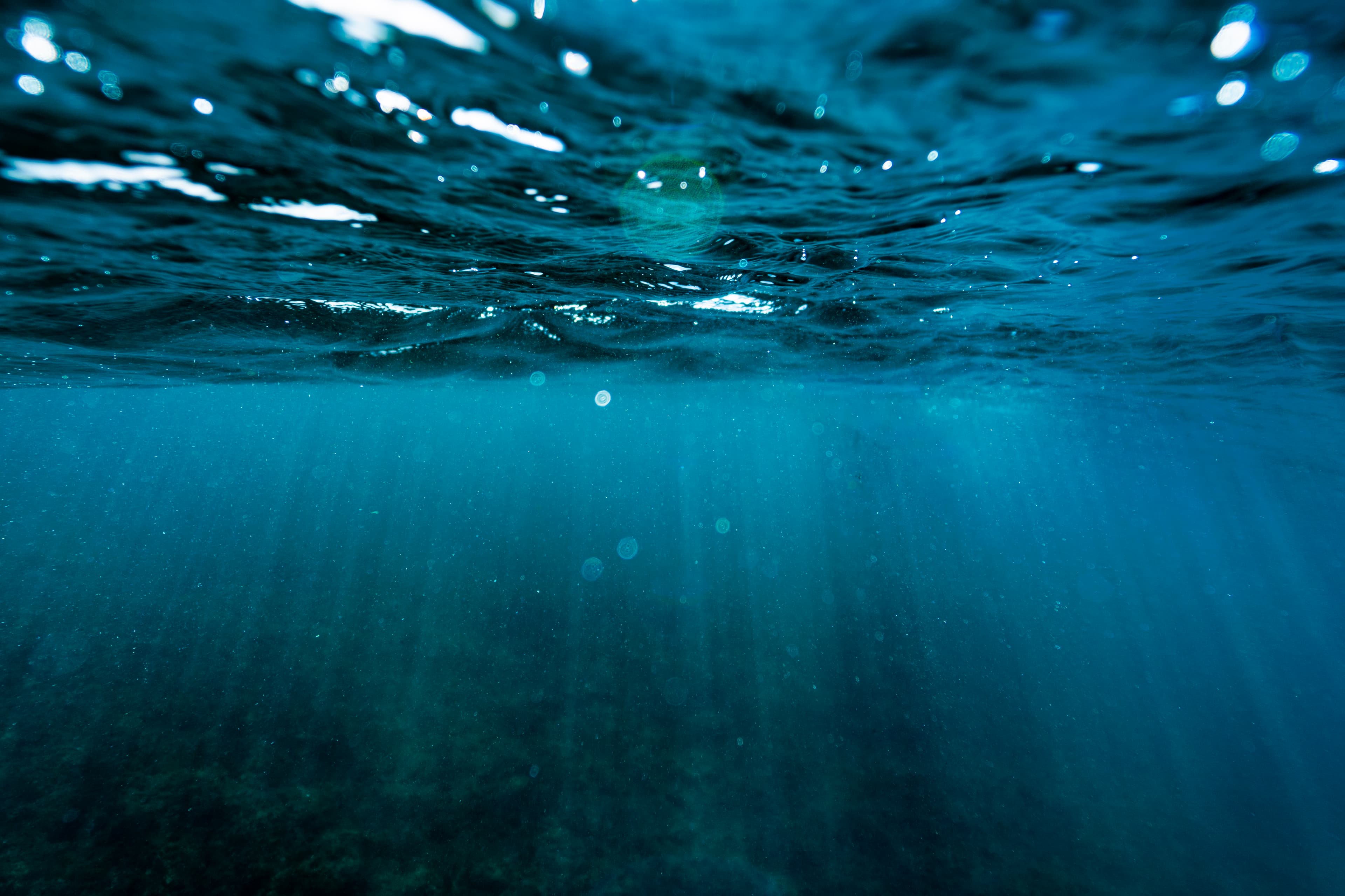 Underwater light rays filtering through teal water — fine art ocean photography print, Whangamata NZ.