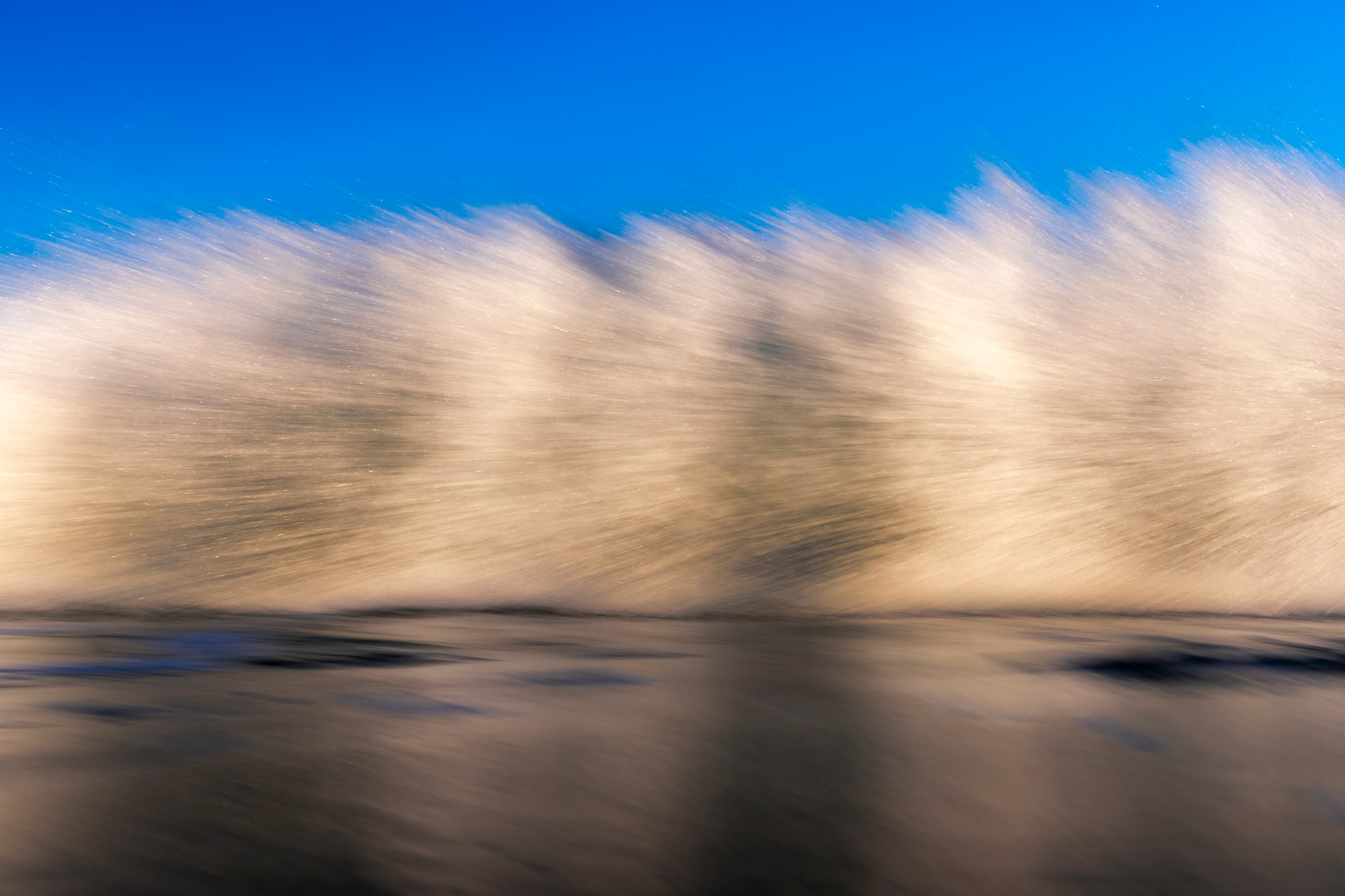 Golden backlit spray bursting into a blue sky — fine art ocean photography print, Whangamata NZ.